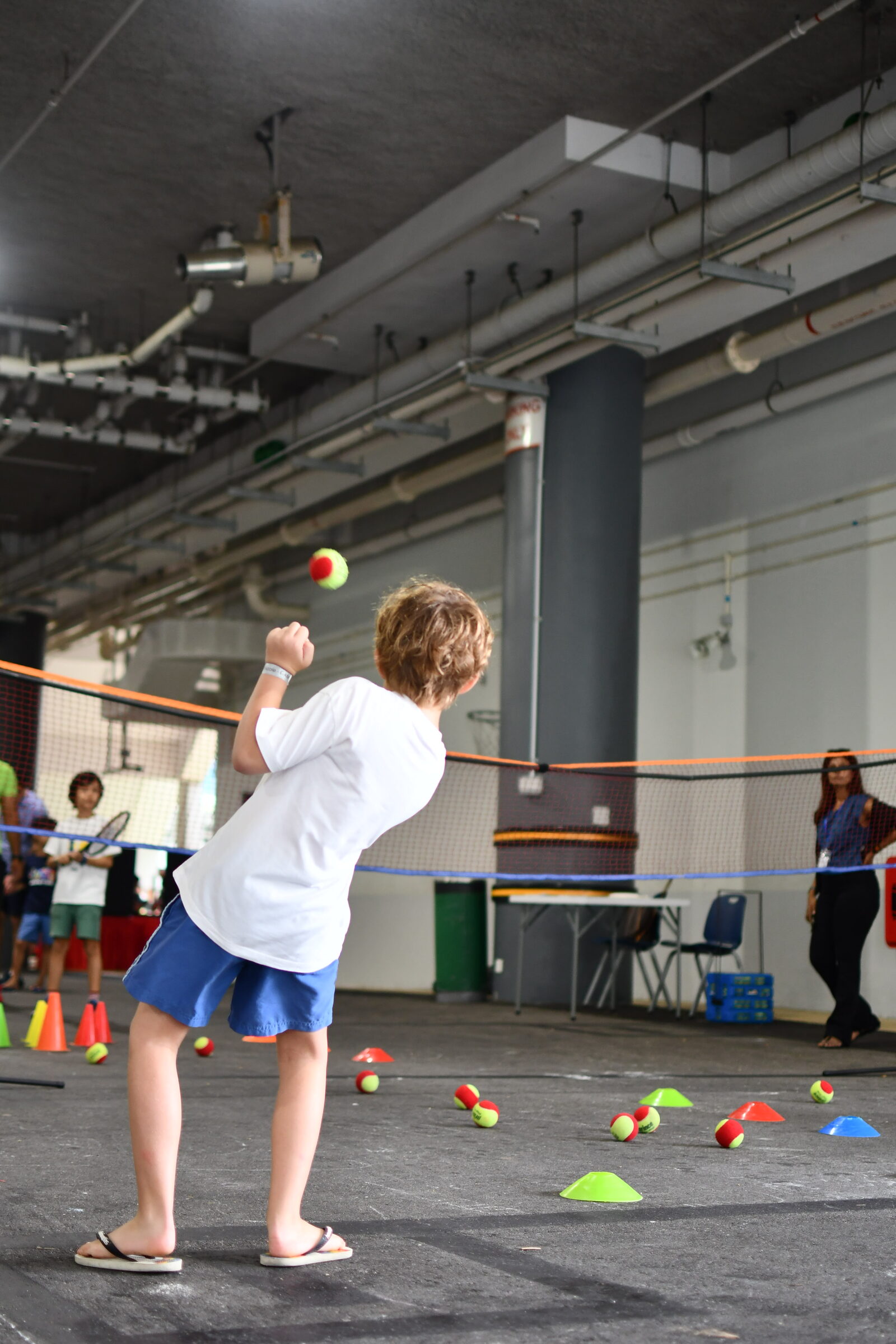 A participant playing a racket sport in a marked-out activity zone at a LyfeGo multi-sport event
