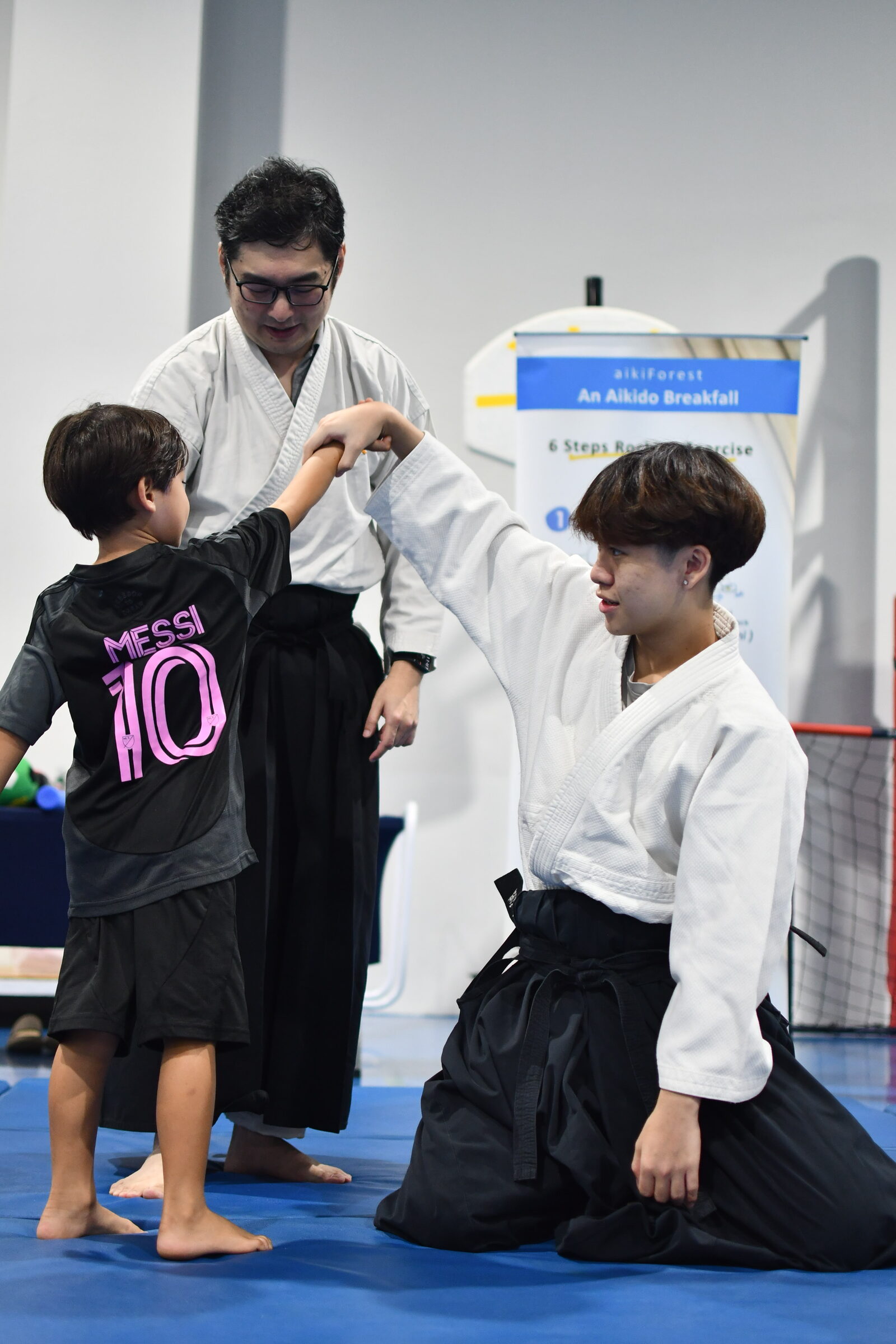 An aikido instructor guiding two participants through a technique at a LyfeGo multi-sport event